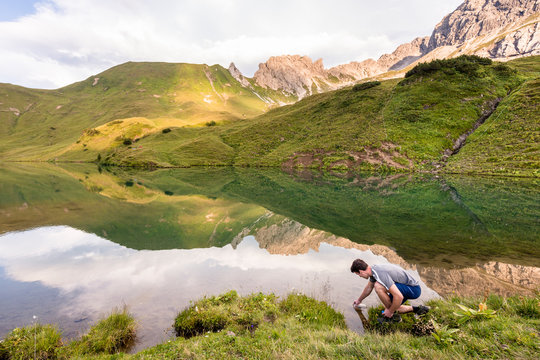 Schrecksee, Allg&permil;u, Bavaria, Germany: A male hiker refilling  a water bottle with the clear water of the Schrecksee, a small alpine lake in the Allg&permil;u Alps.