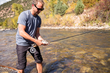San Miguel River, near Telluride, Colorado, USA: A male fly fisher with his first catch of the day.
