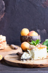 Cheesecake with apricot and crumble, fresh apricots and mint. Wooden background, rustic style. Copy space.