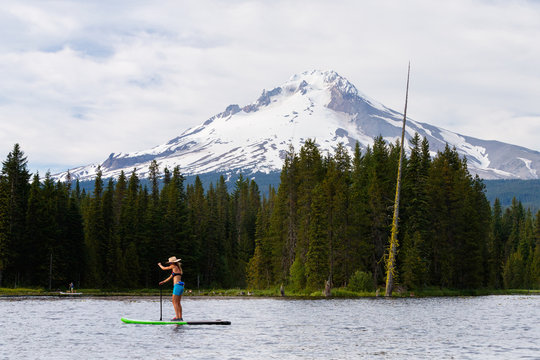 A woman stand up paddleboards at Trillium Lake, a popular recreation spot near the base of Mount Hood, Oregon.