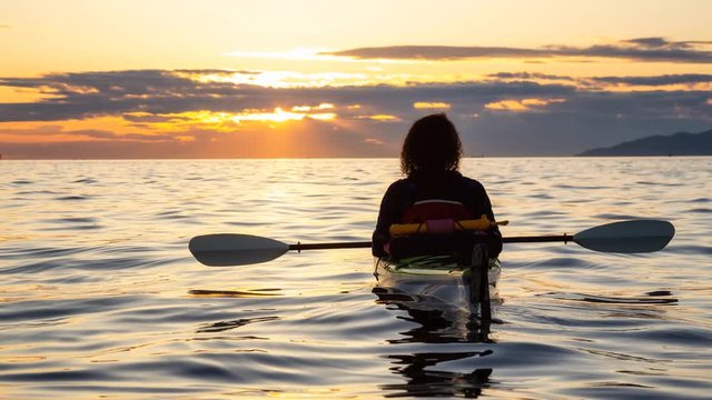 Girl Sea Kayaking during a vibrant sunny summer sunset. Taken in Vancouver, BC, Canada. Still Image Continuous Animation