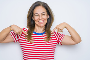 Fototapeta premium Middle age senior woman standing over white isolated background looking confident with smile on face, pointing oneself with fingers proud and happy.