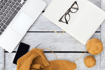 Women's hobby. Crochet and knitting. Working space.  Cup of coffee , balls of mustard yarn, needles, knitwear, crochet hooks on the wood table in the cozy home.