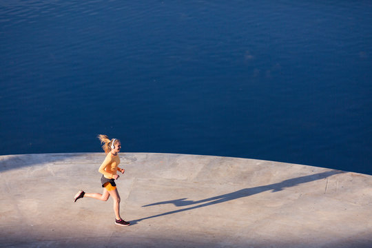 Olympia Park, Munich, Bavaria, Germany: A young female runner running along the lake.