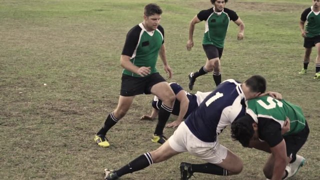 Rugby player with ball tackling the opponent during the match. Rugby players in action on the ground.