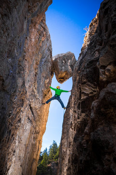 Kyle Vassilopoulos having some fun while climbing below a large chock stone in slot canyon at Natural Bridge State Park.