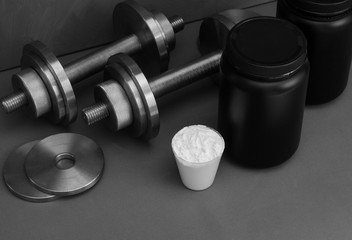 Obraz na płótnie Canvas Sports nutrition with dumbbells on a gray background.