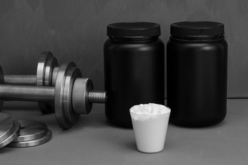 Sports nutrition with dumbbells on a gray background.