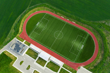 Aerial view from below on a large green soccer field with white lines aligned in a city stadium with territory for football fans. Playing football at the stadium. Texture of football field. Copyspace