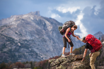 Woman helping man while climbing on rock