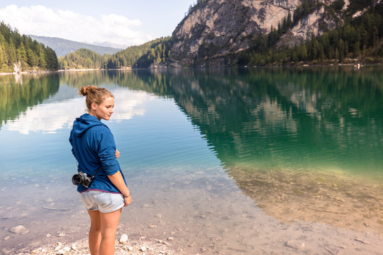 Lake Prags, Prags Dolomites, South Tyrol, Italy: A woman with an analog camera hanging over her shoulder at the shore of Lake Prags.