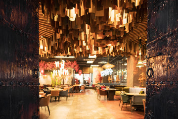 Blurred image of the interior of a large beautiful restaurant with bright lighting. The waitress comes to the working bar and the bartender, gives visitors a menu and goes for a drink. Defocused staff