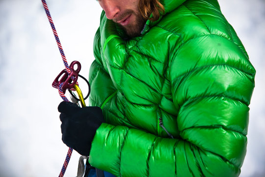 Midsection of man in puffer jacket holding safety harness
