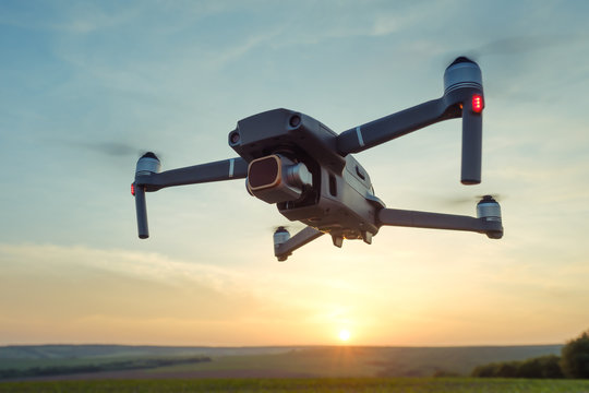 Professional shooting drone flies in the air at low altitude against a blue sky and orange sunset. Drone makes photos. Modern new technology. Ready background with place for your text.