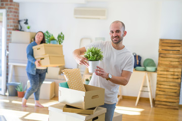 Young couple moving to new apartment, handsome man moving cardboard boxes and smiling happy