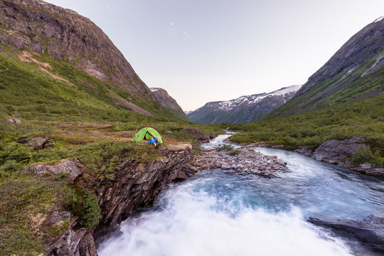 Eidsdalselva, M&macr;re og Romsdal, Norway: A male hiker at his camp on a cliff by the river.