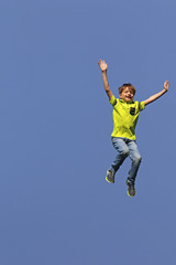 Fototapeta na wymiar Junge springt in die Luft, im Hintergrund blauer Himmel