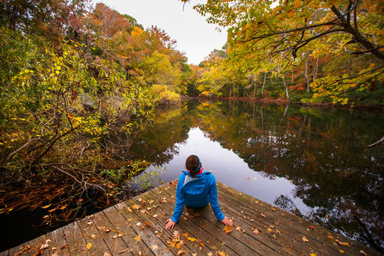 A woman sits on a fishing pier at a freshwater pond along the Discovery Trail in the Nags Head Woods Preserve.