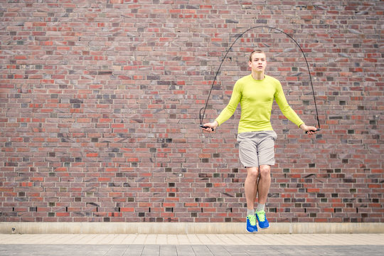 Basketball athlete skipping in front of a brick wall as part of his workout.