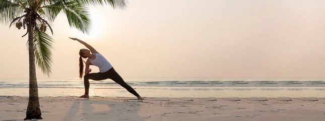 Poster Yogavrouw die yogaoefening op het strand doen. © May_Chanikran
