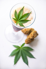 Cold glass of beer with cannabis leaf and nugs isolated over white