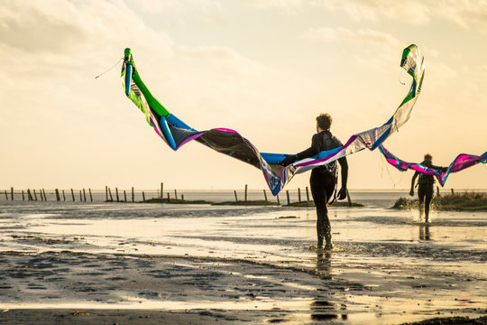 Kiteboarders with their kites during sunset at the coast of the German Sea in St. Peter Ording, Germany.