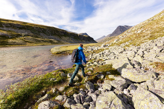 Rondane National Park, Norway: A male hiker hiking along the the river that flows from the Rondvassbu lodge towards Otta and comes by the parking in Spranget.