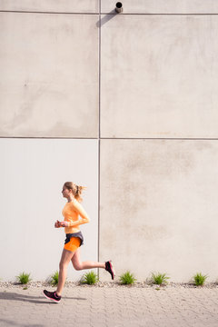 Olympia Park, Munich, Bavaria, Germany: A young female runner running through the olympic village in the morning.