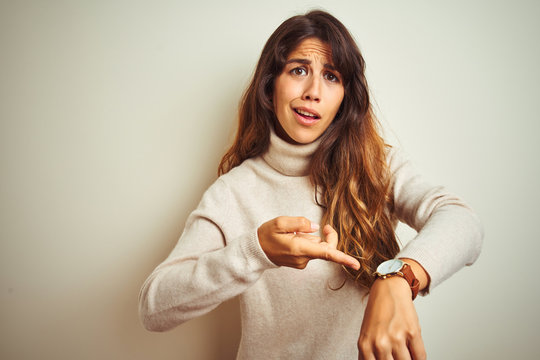 Young beautiful woman wearing winter sweater standing over white isolated background In hurry pointing to watch time, impatience, upset and angry for deadline delay