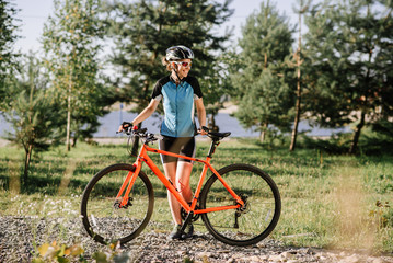 Fototapeta premium Young pretty woman holding bicycle outdoors at the park