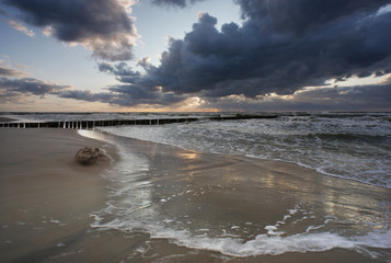 Morze zachód słońca - falochron z chmurami i sztormem