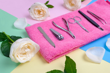 set of tools for manicure on a pink terry towel in the surrounding of pink flowers on a bright background