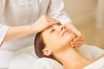 Facial massage to a beautiful girl lying in a beauty clinic.