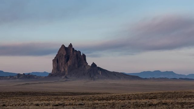 Dramatic panoramic landscape view of a dry desert with a mountain peak in the background during a vibrant cloudy sunrise. Taken at Shiprock, New Mexico, United States. Still Image Continuous Animation