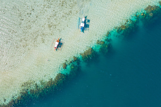 From above drone view of boats at rest on shallow of sandy seashore