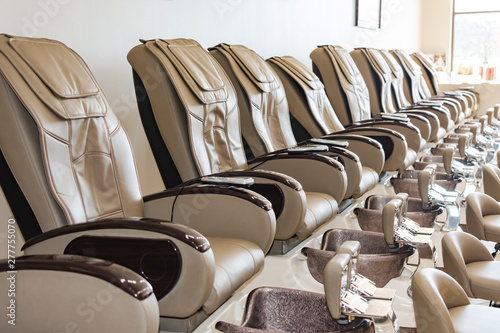 A Row Of Pedicure Chairs Towards The Front Of A Background Blurry Wall