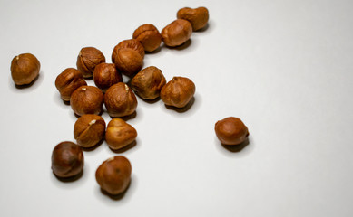 Several varieties of nuts are located on a white sheet of paper.