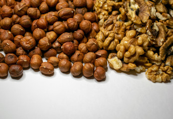 Several varieties of nuts are located on a white sheet of paper.