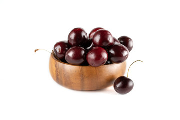 Red Cherry in a wooden cup on a white isolated background. One cherry lies next to the plate