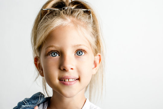 Beautiful blond girl of seven years old, big blue eyes, close-up, white background