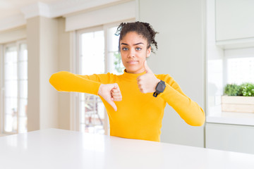 Beautiful african american woman with afro hair wearing a casual yellow sweater Doing thumbs up and...