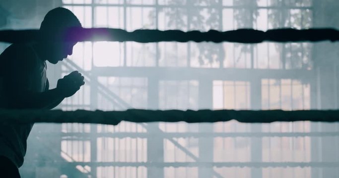 Cinematic slow motion shot of a professional young muscular african man is practicing shadow boxing work out in a ring. 