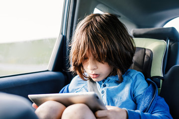 Child using a tablet while in car seat