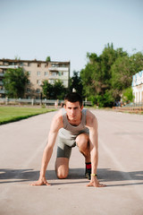 young runner athlete in the low start position on the sports track on stadium outdoor