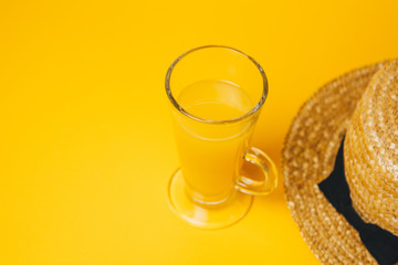 concept of relaxation and thirst on the beach. a glass of lemonade on a yellow background with a...