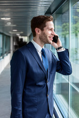 Erfolgreicher Business Man im blauen Anzug telefoniert und ist zufrieden