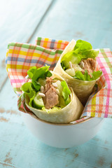 Sandwich wrap with tuna fish, lettuce and cucumber, on a wooden blue table