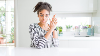 Beautiful african american woman with afro hair wearing casual striped sweater Holding symbolic gun with hand gesture, playing killing shooting weapons, angry face