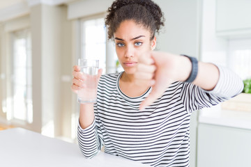 Young african american girl drinking a fresh glass of water with angry face, negative sign showing dislike with thumbs down, rejection concept