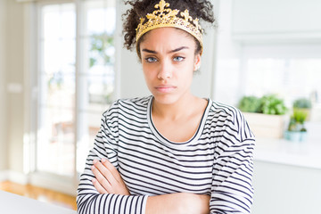 Young african american girl wearing golden queen crown on head skeptic and nervous, disapproving expression on face with crossed arms. Negative person.